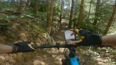 el hombre se detiene en el camino mientras anda en bicicleta de montaña para ver dónde está usando el teléfono montado en la bicicleta para navegar por los próximos movimientos