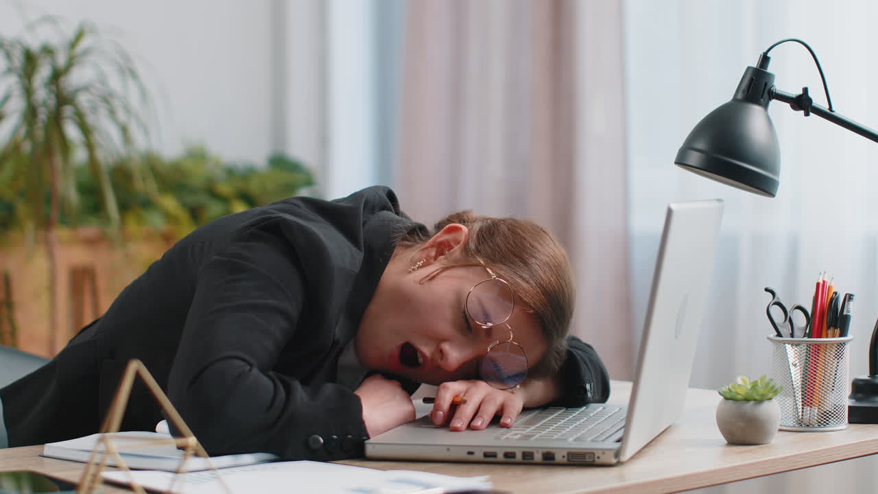 Bored sleepy business woman worker working on laptop computer yawning falling asleep at home office