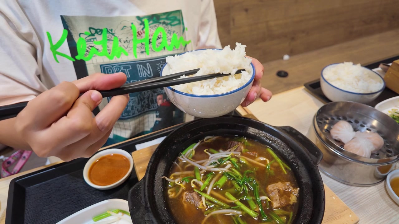 Cận cảnh một thực khách dùng đũa ăn cơm với canh bò ở Bangkok.