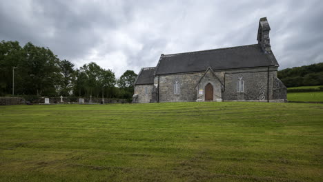 time lapse of a historical church in rural landscape with grass cut in ireland during a cloudy day