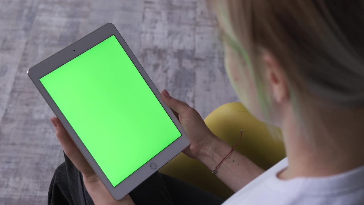 mujer con una tableta pc en las manos con una pantalla verde, llave de croma.