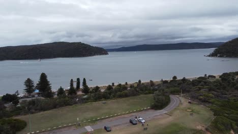 drone volando sobre un aparcamiento revelando una bahía en el otro lado de la península