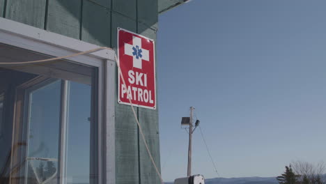 ski patrol red sign posted on the exterior wall of a cabin, clear day