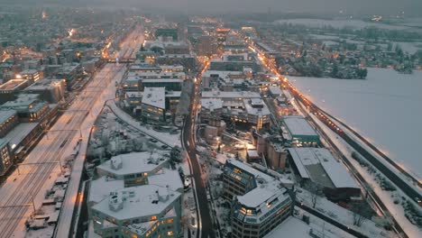 snowy urban dusk: aerial view of traffic on city streets lit by evening lights