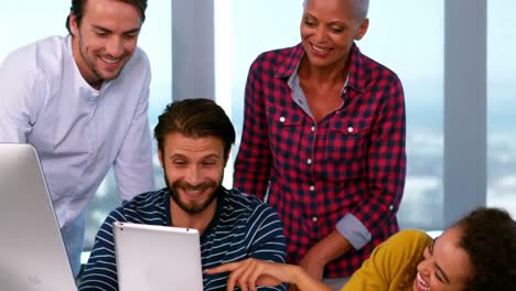 Happy-colleagues-discussing-over-the-digital-tablet-at-desk