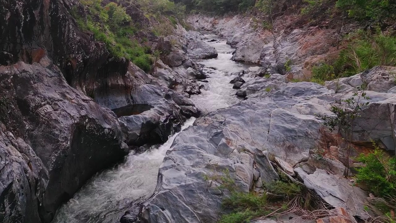 Fiume São Miguel che scorre attraverso un canyon di quarzite nella Serra do Segredo, Chapada dos Veadeiros, Goiás, Brasile, circondato dalla vegetazione del Cerrado e da formazioni rocciose erose, discesa drone orbita parallasse.