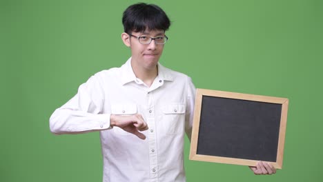 young asian businessman holding blackboard while giving thumbs down