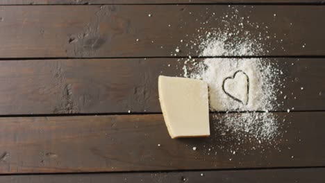 Video-of-block-of-hard-cheese-and-heart-drawn-in-grated-cheese-on-rustic-table-with-copy-space