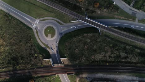 círculo de tráfico en una calle plana con coches que pasan combinados con vías de tren grabadas desde arriba desde un dron