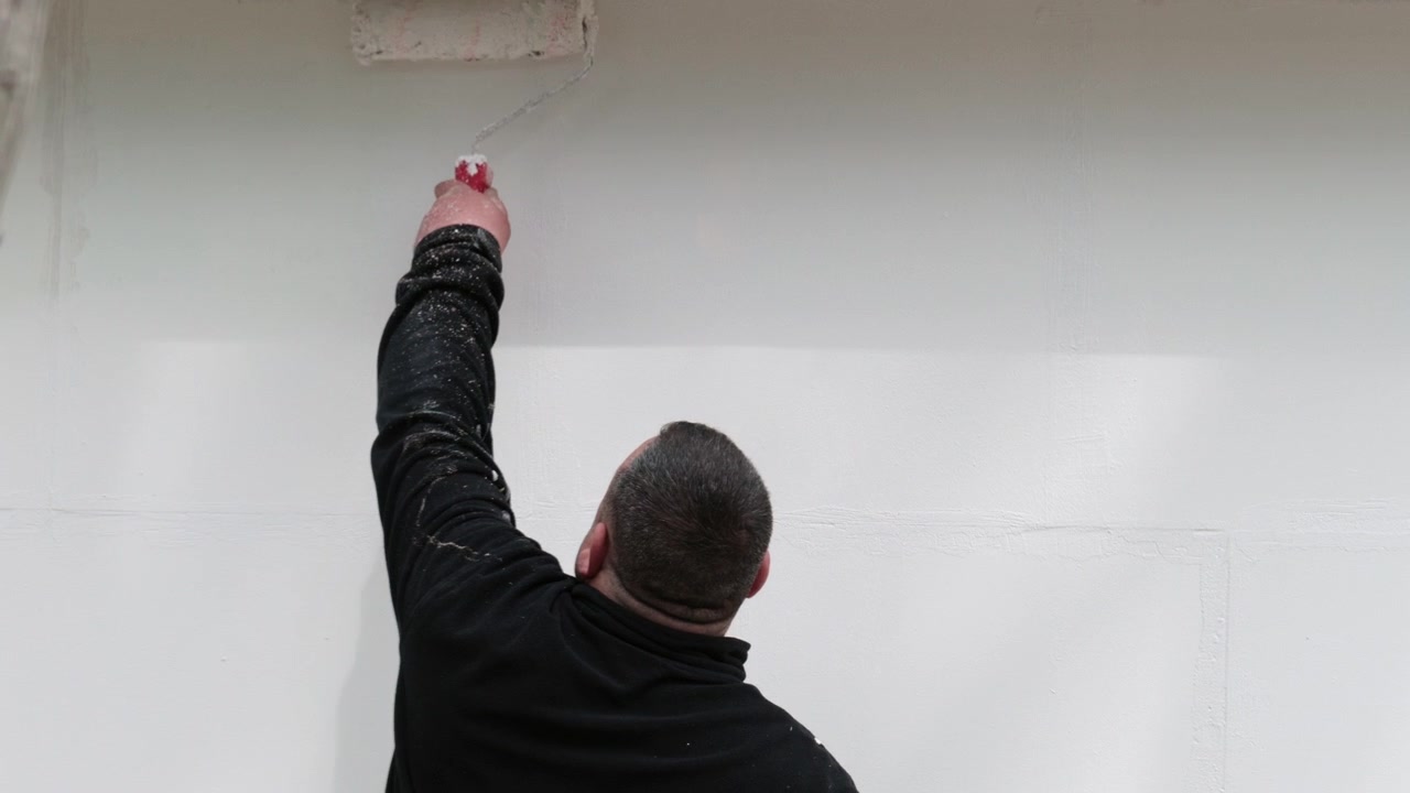 Worker painting a wall with a roller, renovation process in progress