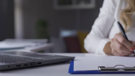 senior business woman working from home taking notes and typing on laptop keyboard.
