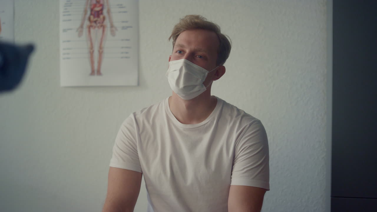 Giovane paziente in consultazione con uno specialista medico, seduto in clinica, in primo piano.