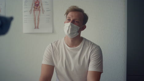 Young-guy-patient-consulting-with-medical-specialist-sitting-clinic-close-up.