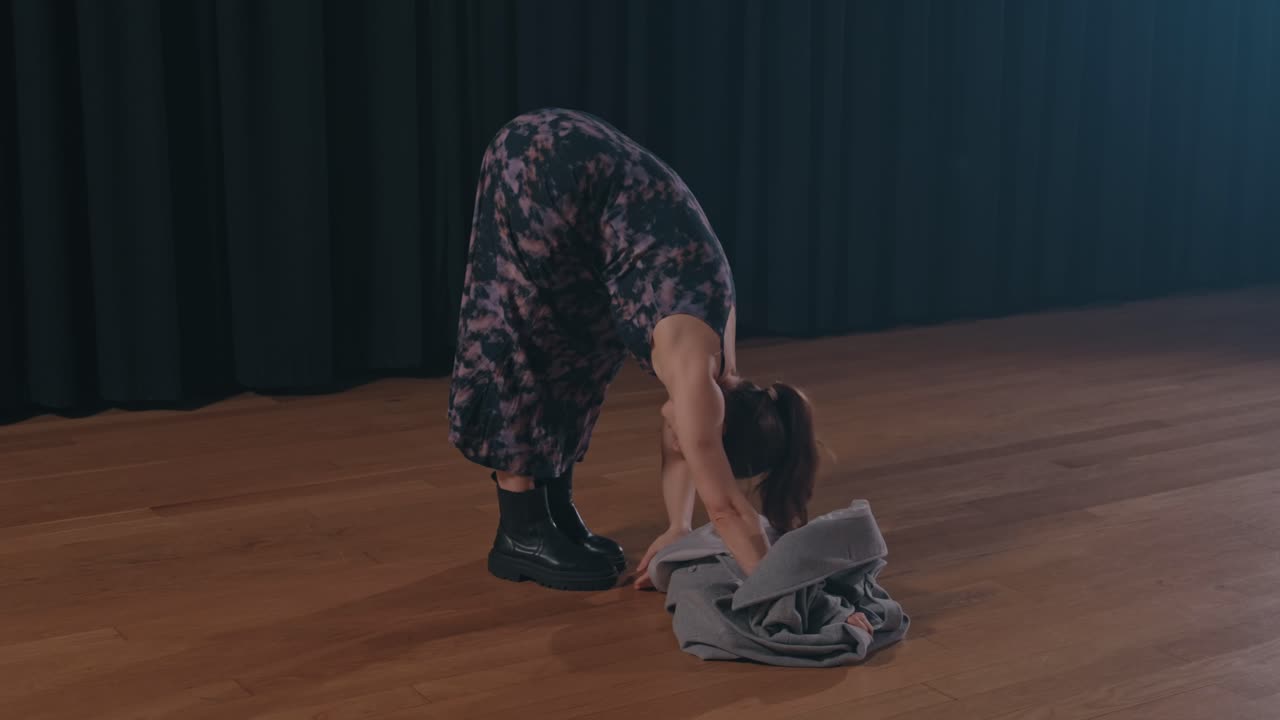 emotive dance performance with coat on empty wooden stage
