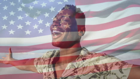 animación de la bandera de los estados unidos de américa sobre un feliz hombre afroamericano en la playa