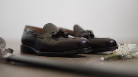 polished dark brown leather shoes with a boutonnière on a wooden surface