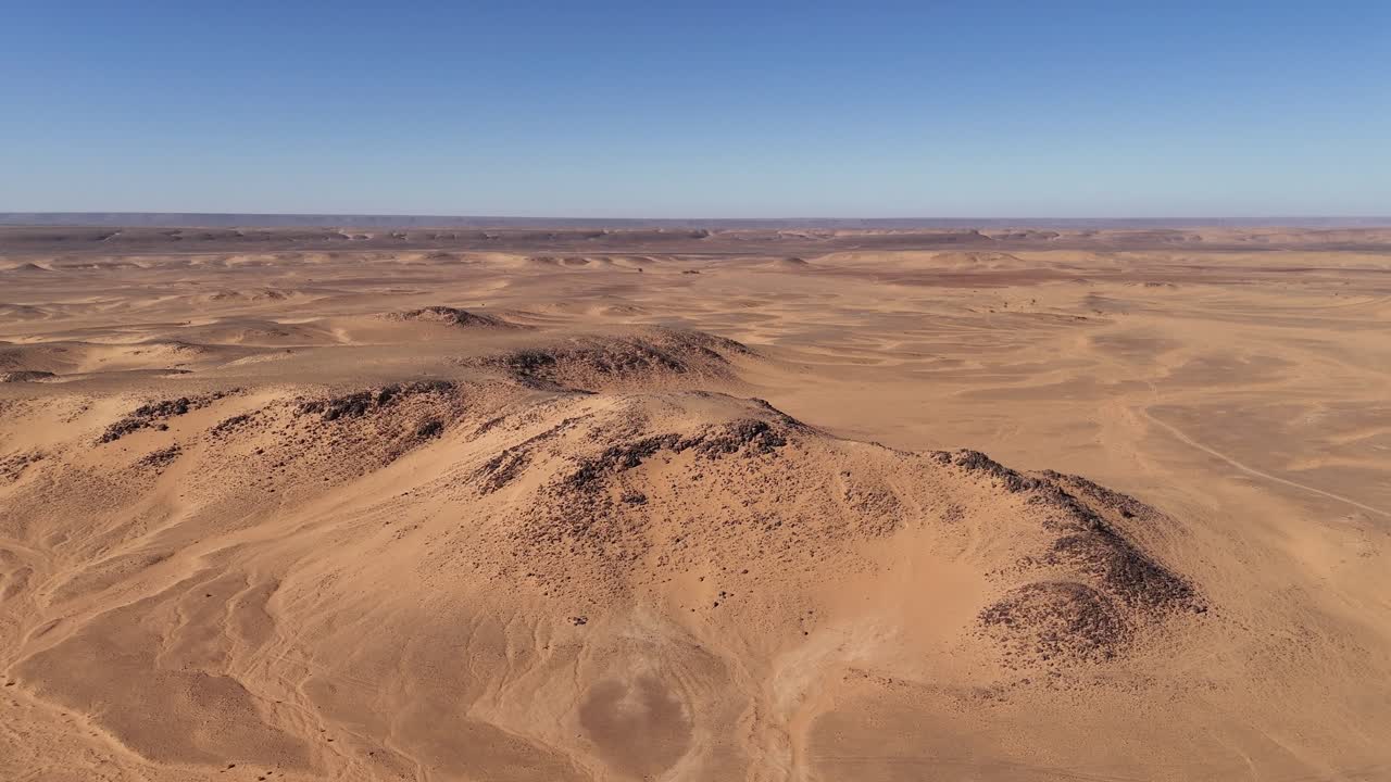 Drone aerial view of the Eye of the Sahara in Mauritania, an iconic natural wonder with striking circular patterns in the vast desert landscape against blue sky