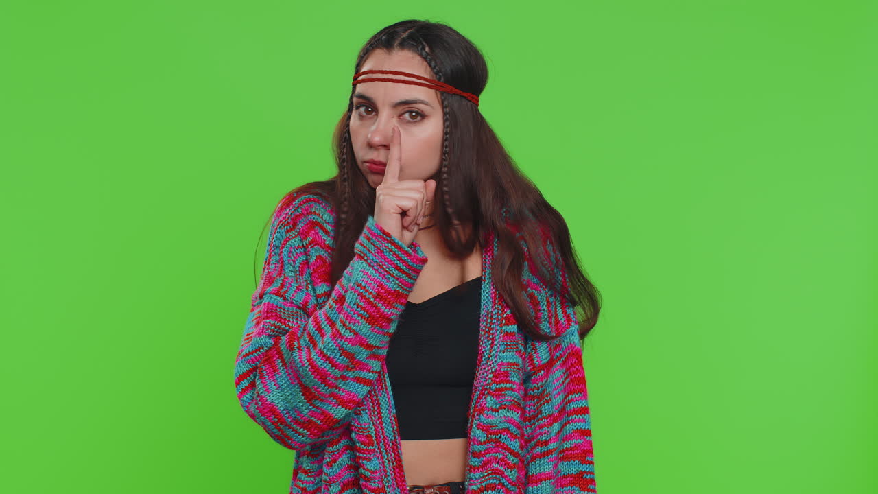 Young woman presses finger to lips makes silence gesture sign do not tells secret stop gossip