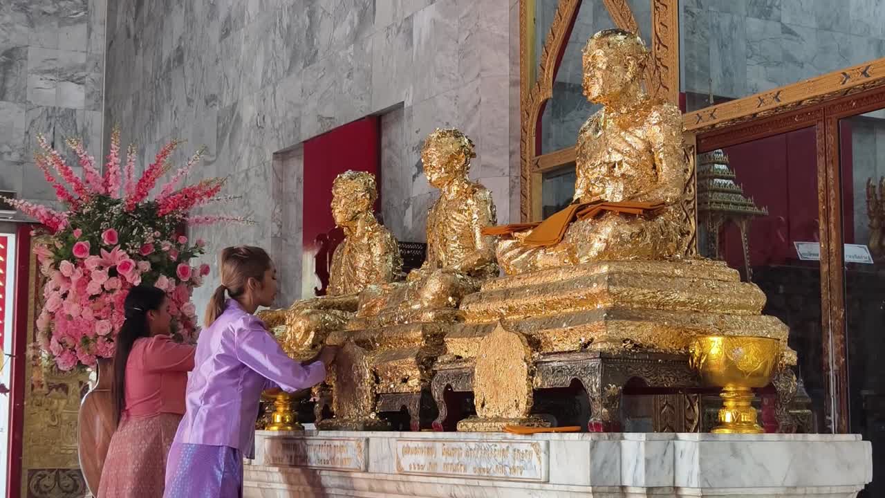 estatuas de oro y adoradores en un templo tailandés