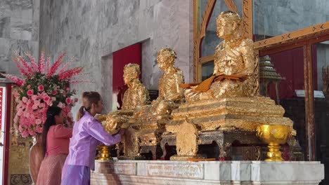 golden statues and worshipers at a thai temple