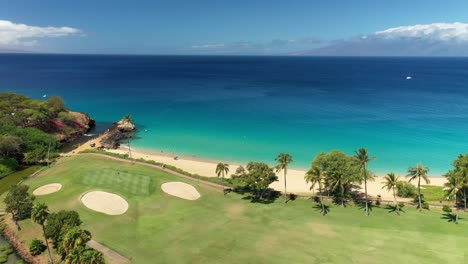 slow aerial spinning view of white birds over a golf course and beach in maui, hawaii