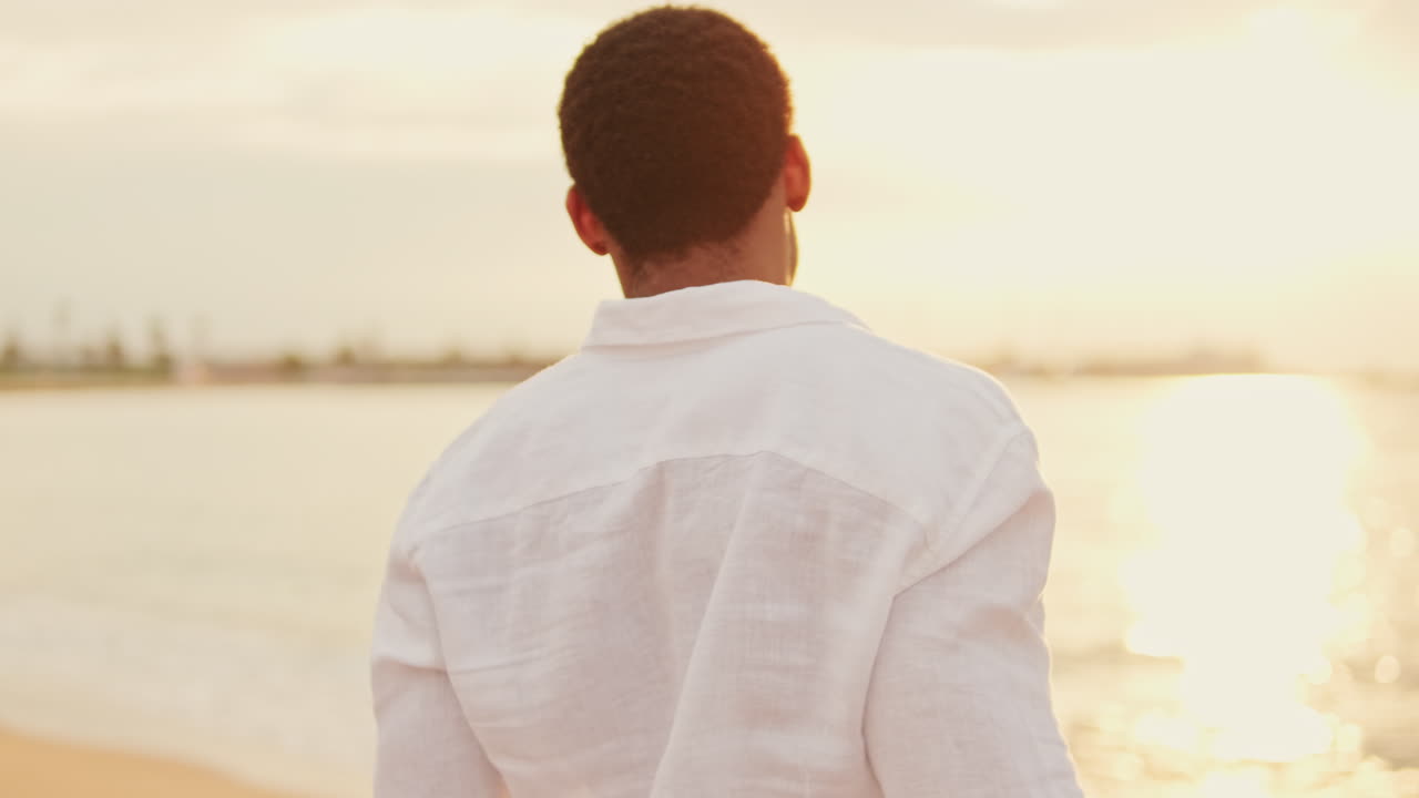 Thoughtful Young Man Looking at the Ocean at Sunset