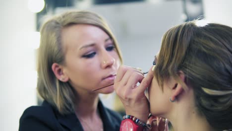 Vista-De-Cerca-Del-Maquillador-Aplicando-Sombra-De-Ojos-En-El-Párpado-Con-Una-Brocha-De-Maquillaje.-Maquillaje-Profesional.-Tiro-En-Cámara-Lenta