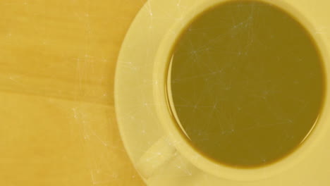 ceramic coffee cup sitting on light wooden table showing warm yellow tone steaming gently