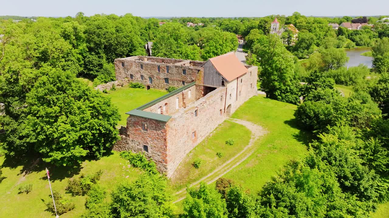 Aerial view of ancient fortress ruins in Aizpute, Latvia with drone movement