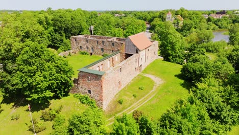 aerial view of ancient fortress ruins in aizpute, latvia with drone movement