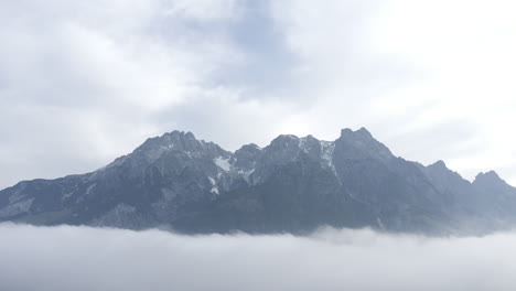 majestic mountain peaks in austria with clouds below, a peaceful and natural scene