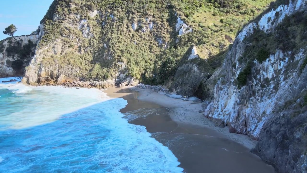 Ripresa ravvicinata in discesa con drone di una piccola spiaggia appartata sulla costa della Nuova Zelanda. 4k 59.94p.