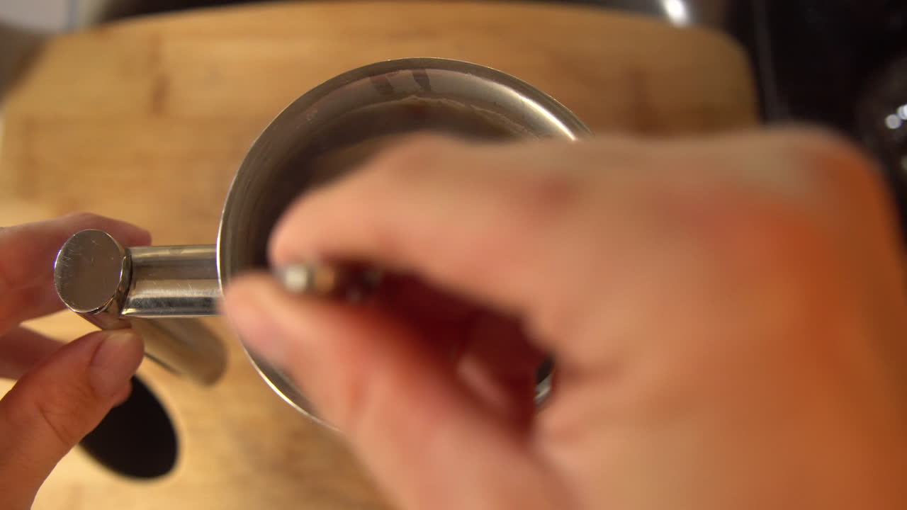 Draufsicht eines Mannes, der den Kaffeesatz in einer French Press umrührt
