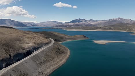 backward aerial view of the maule lagoon at the pehuenche border crossing between chile and argentina on a sunny day with the andes mountains in the background