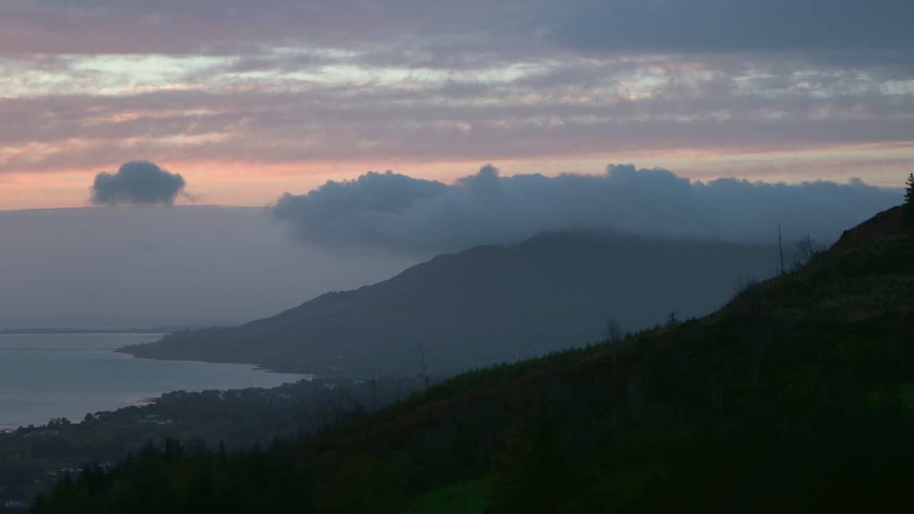 amanecer azul y rosa, nubes al atardecer, con montañas y mar