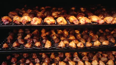 a large batch of golden-brown smoked chicken wings arranged on a grill rack. the wings appear juicy and well-cooked, ideal for barbecue or party servings.
