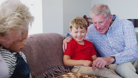 Grandparents-Playing-Board-Game-Of-Draughts-With-Grandchildren-At-Home