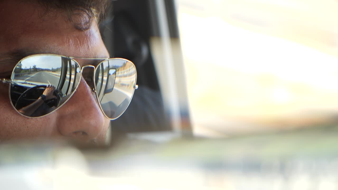 conduciendo por la autopista, primer plano de las gafas de sol de un hombre con la carretera y el volante reflejados en ellas