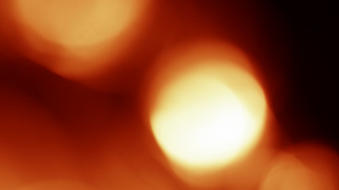 Warme abstrakte Bokeh-Lichtlecks, die sich auf dunklem Hintergrund bewegen