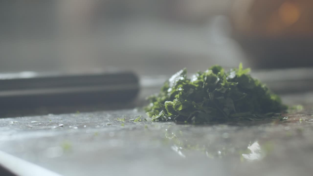 fabricante de pizza cortando perejil en la cocina
