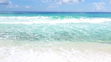 waves from the clear tropical waters of the gulf of mexico break on a beach of cozumel island, mexico