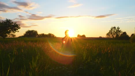 Silhouette-Eines-Mannes,-Der-Während-Der-Wunderschönen-Goldenen-Stunde-Dehnübungen-Inmitten-Von-Feldern-Macht