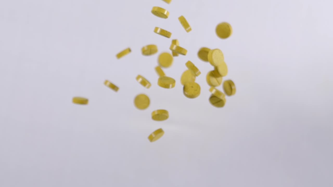 Ripresa al rallentatore di pillole mediche gialle di curcumina che volano nell'aria, composto fenolico.