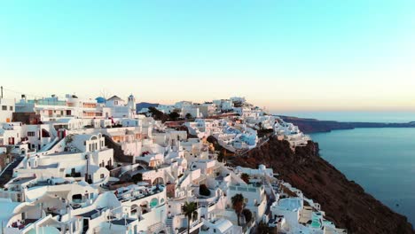 Toma-Aérea-Cinematográfica-Del-Famoso-Pueblo-De-Oia-En-Santorini,-Grecia-Al-Atardecer