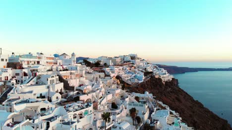 toma aérea cinematográfica del famoso pueblo de oia en santorini, grecia, al atardecer