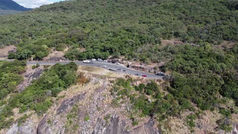 drone backing away from a rugged coastline with a cliff and mountains in the background