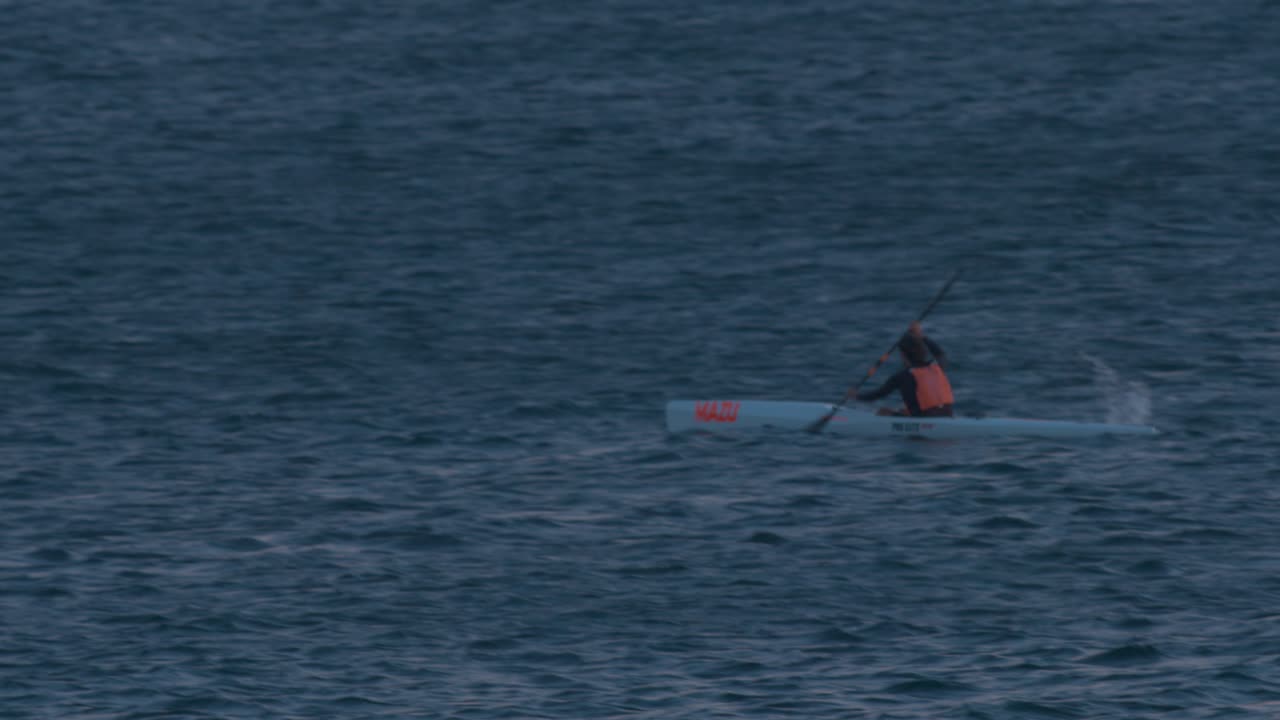 vista aérea de piragüista profesional cabalgando muy rápidamente en el mar entrando en la noche, cascais, portugal