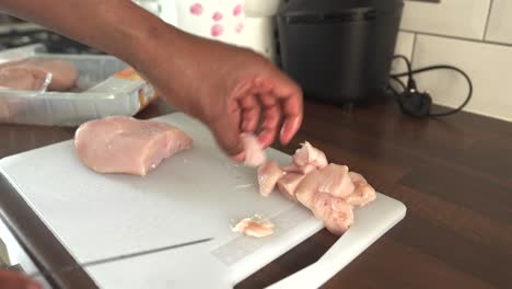 cutting raw chicken on cutting board in home kitchen