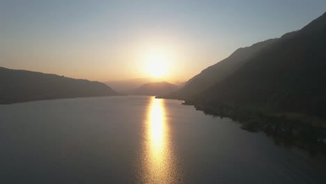 Calm-drone-shot-of-a-beautiful-austrian-lake-with-the-sun-setting-in-the-background