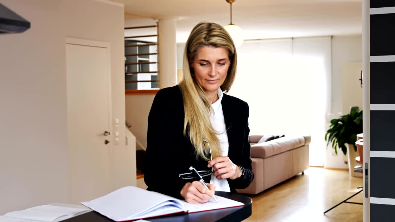 Business Woman Standing and Writing in a Notebook